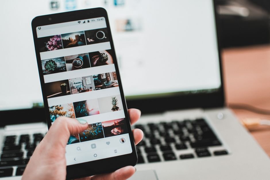 IA slop : LinkedIn lance un bouton pour la signaler Personne consultant les réseaux sociaux sur smartphone, illustrant le contenu généré par IA sur les plateformes professionnelles