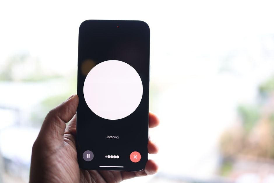 Mode vocal Claude : Anthropic l’étend à ses modèles les plus puissants Main tenant un smartphone affichant une interface d'assistant vocal IA