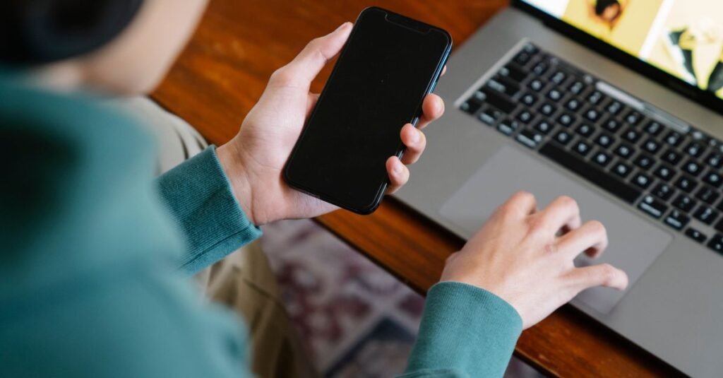Claude Cowork arrive sur mobile et web pour les utilisateurs Max Personne utilisant un ordinateur portable et un smartphone pour du travail à distance