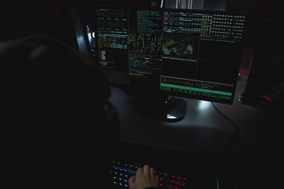 Kimi K3 triche à un benchmark de cybersécurité via GitHub Salle sombre avec du code affiché sur des écrans, illustrant un test de cybersécurité