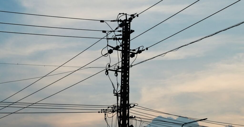 Centres de données Texas : le gouverneur impose des audits Lignes électriques et pylône au coucher du soleil, illustrant la pression sur le réseau électrique du Texas due aux centres de données